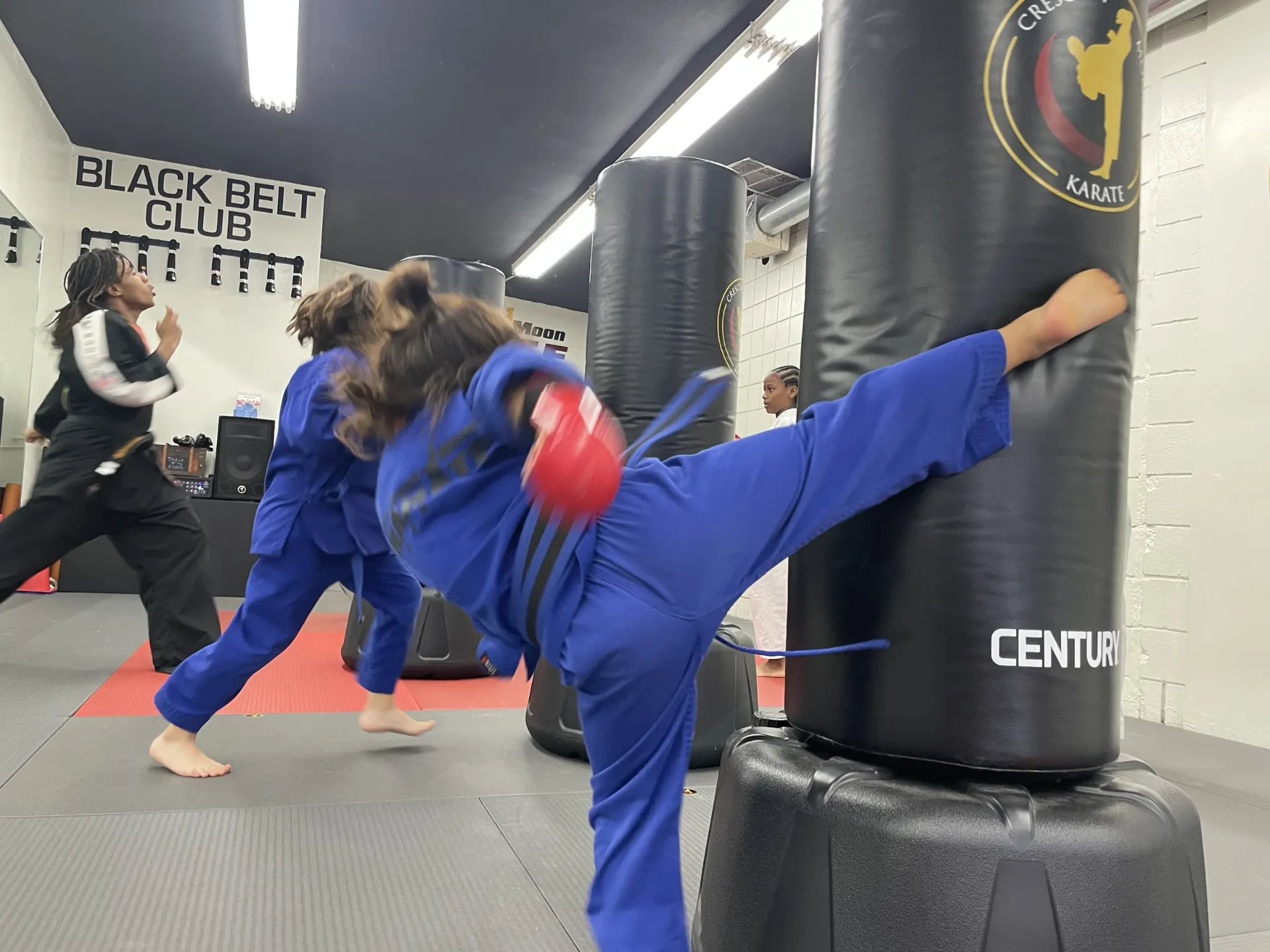 A student practicing a kick on a training bag.